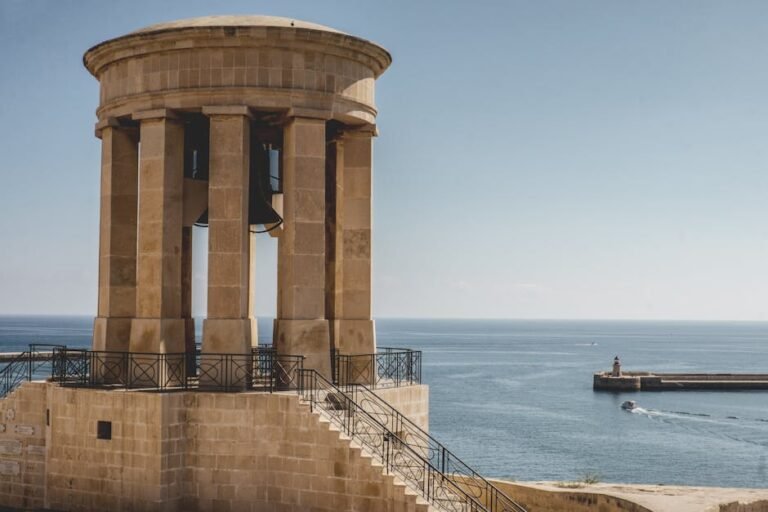 A scenic view of the historic bell tower in Valletta, Malta overlooking a tranquil seascape.
